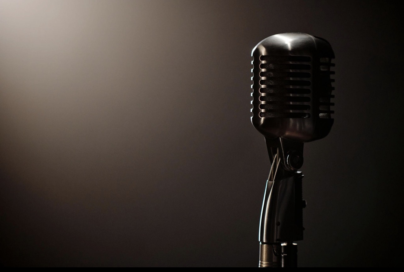 A vintage studio microphone lit against a dark background