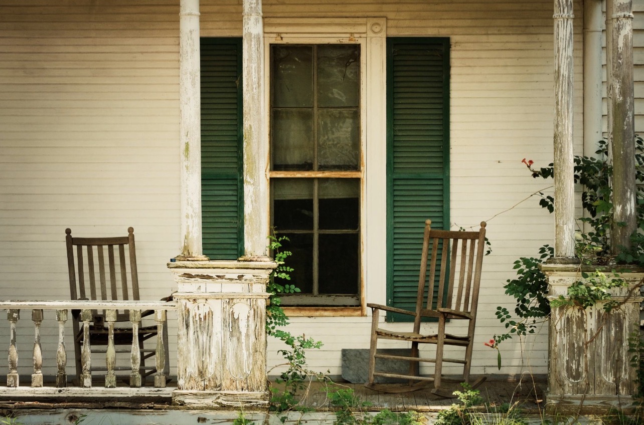 Two weathered rocking chairs on an old farmhouse porch