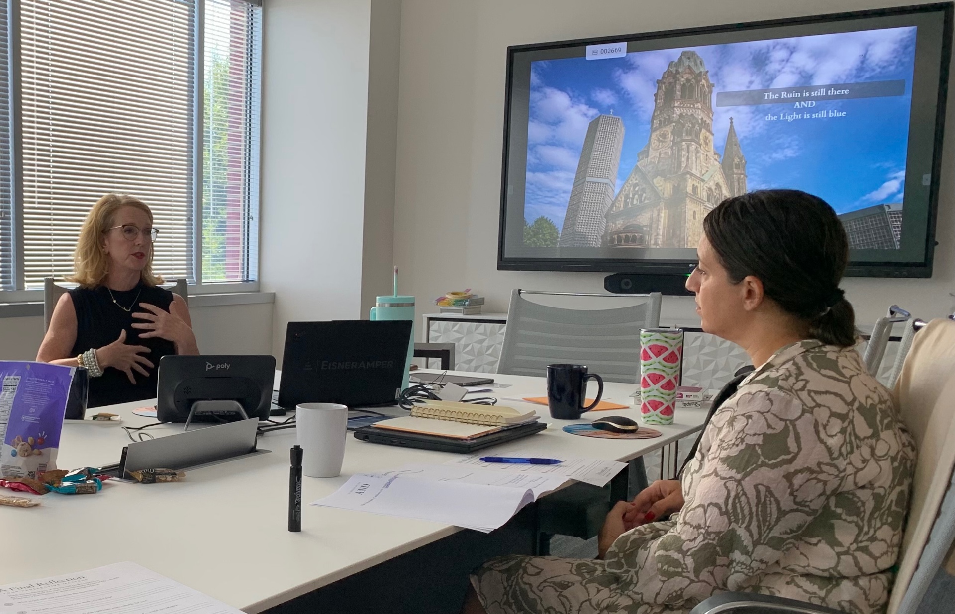 Amy Shortt facilitating The Ruin and the Light at EisnerAmper, with a participant and the Kaiser Wilhelm Memorial Church presentation visible